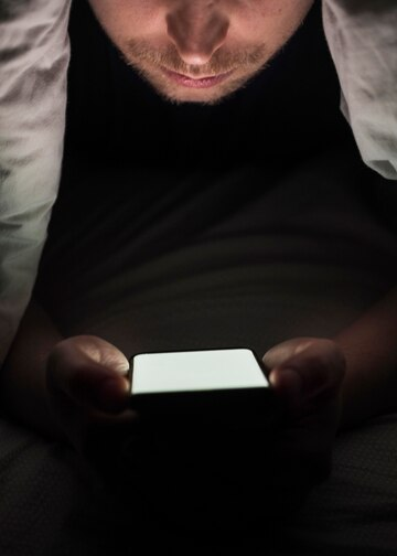 a man sits in the dark with a phone